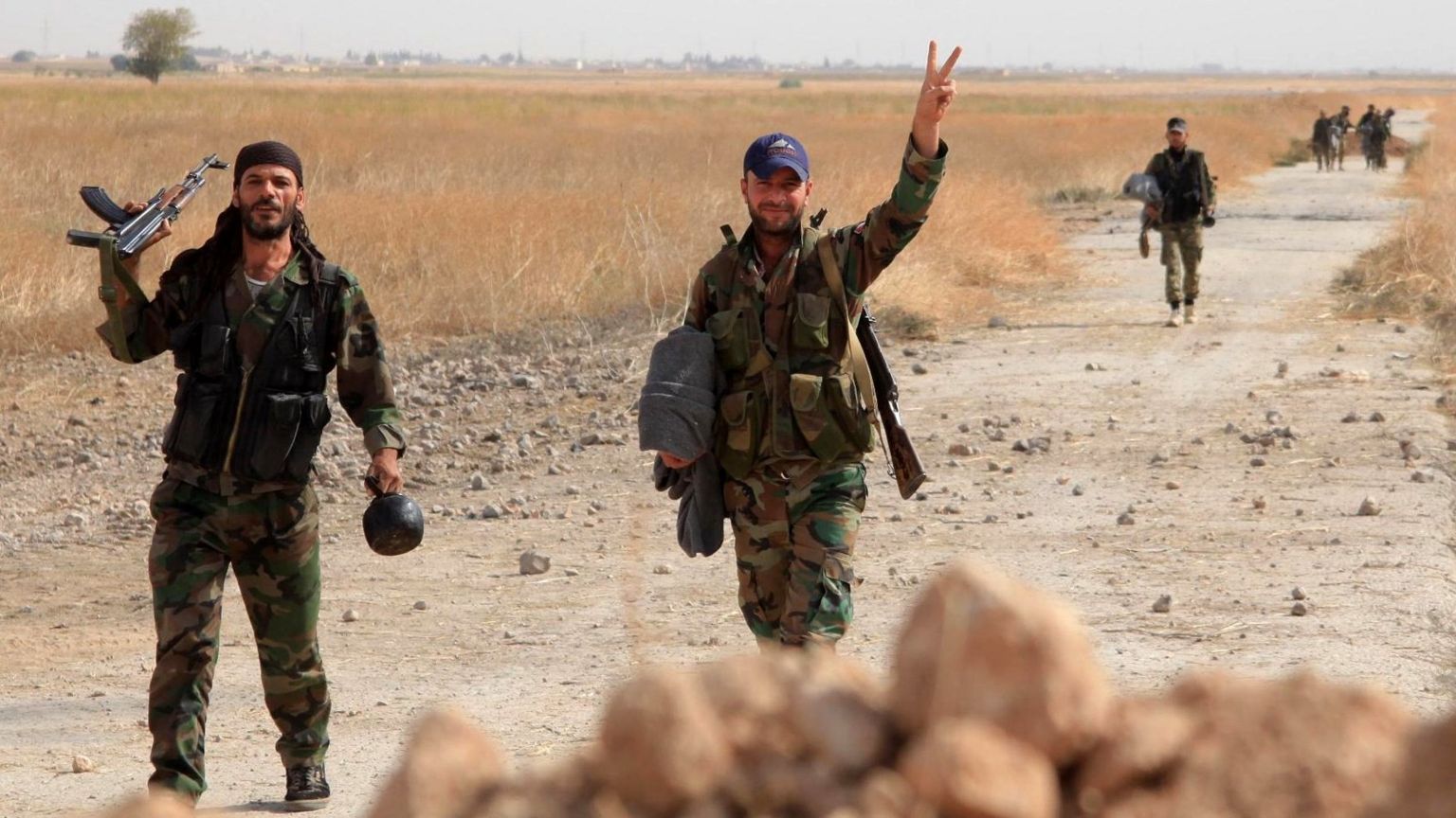 Syrian soldiers gesture as they walk down a road near Kweyris military airport, in Aleppo province (18 October 2015)