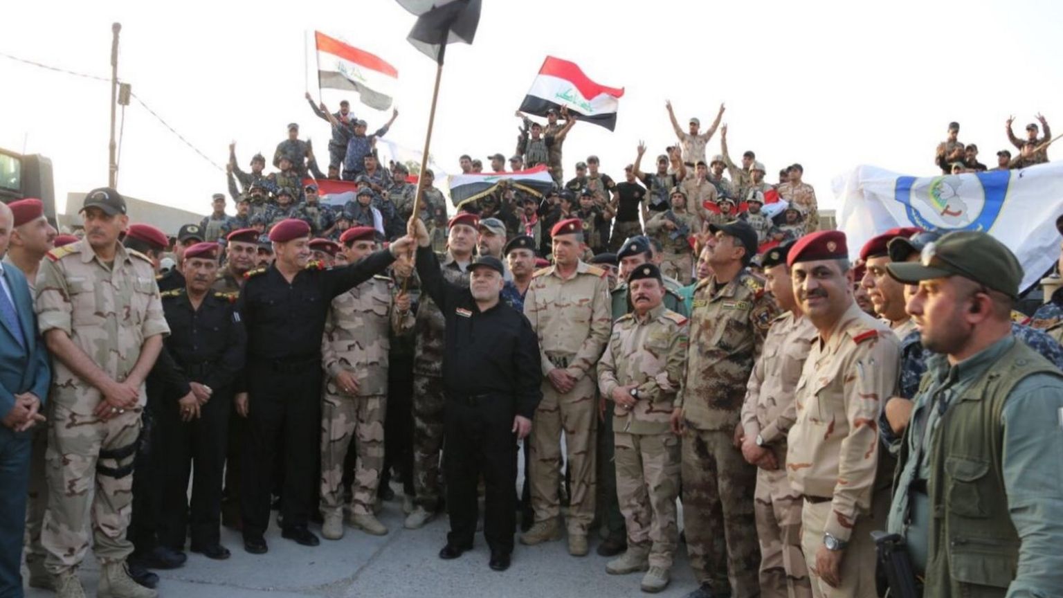 Photograph posted by Iraqi prime minister's office showing Haider al-Abadi (centre) waving a national flag after declaring victory in the battle for Mosul (10 June 2017)