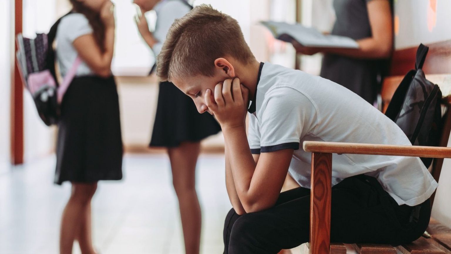 Boy sits along in corridor