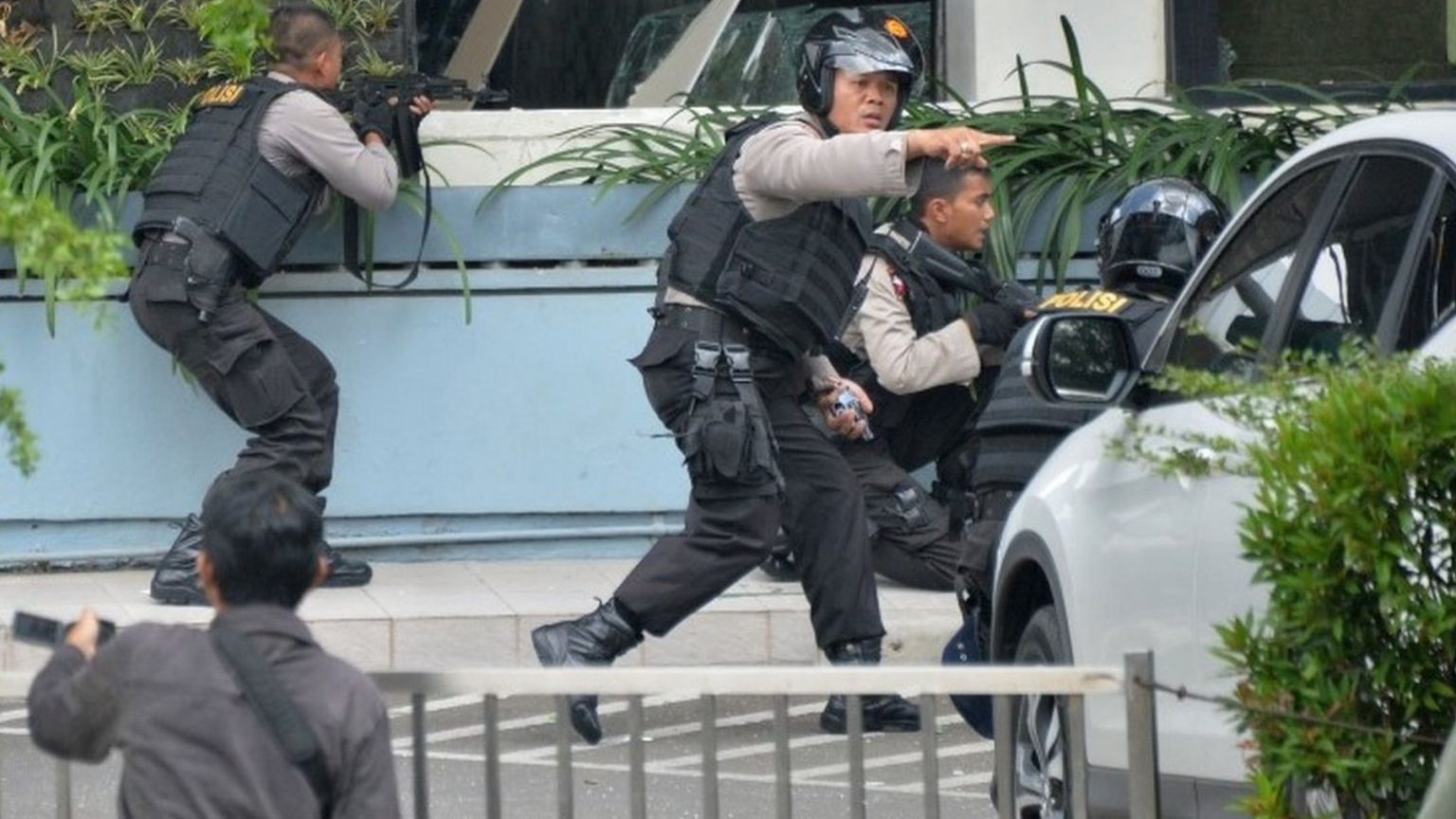 Indonesian police take position and aim their weapons as they pursue suspects in Jakarta