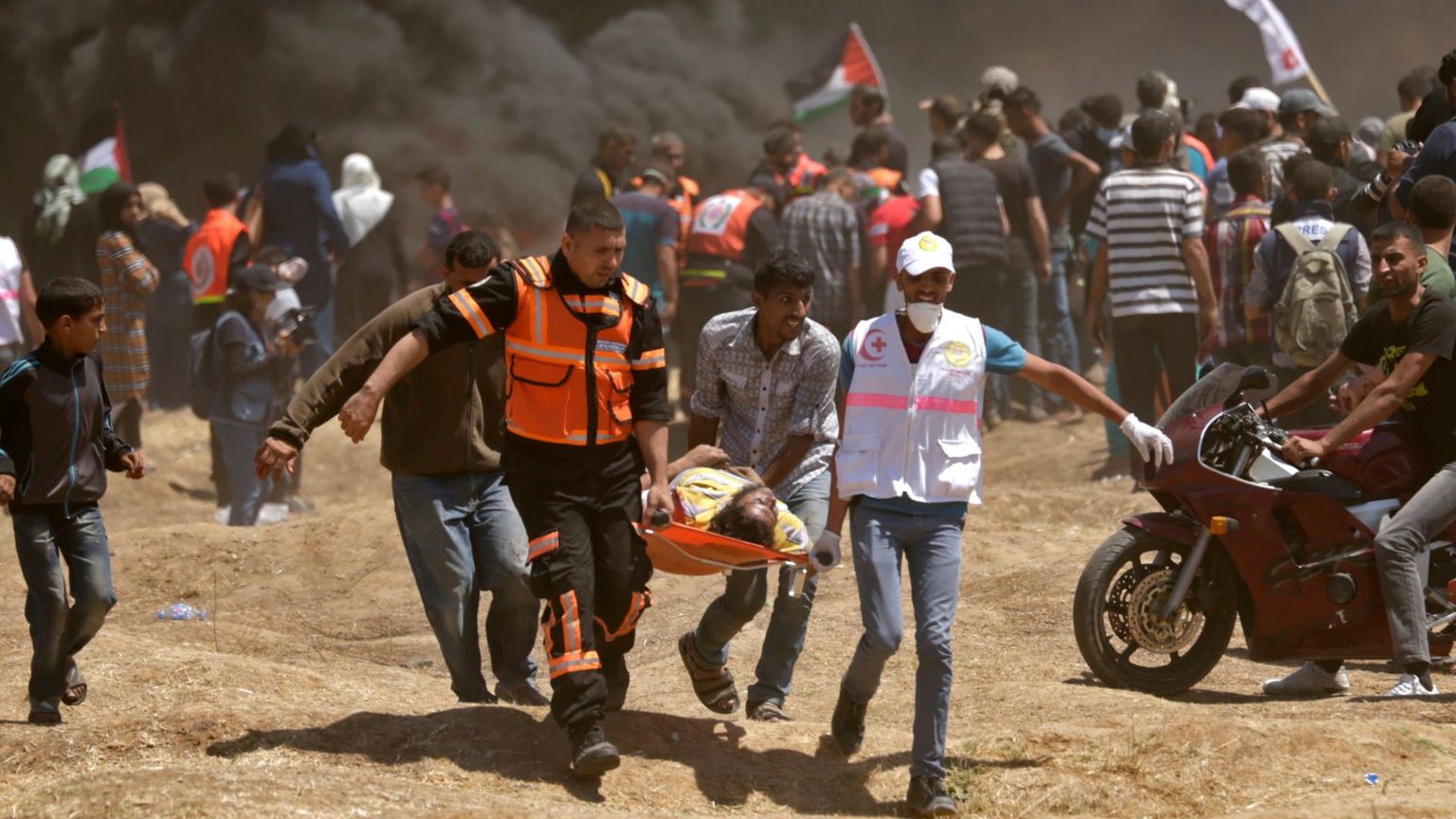 Palestinians carry a person wounded during a protest on the Israel-Gaza border (14 May 2018)