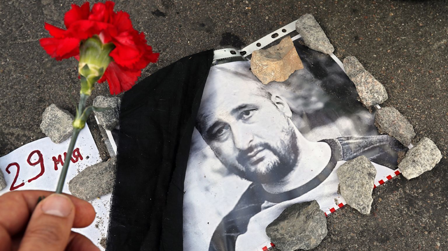 A flower is laid next to a photo of Arkady Babchenko