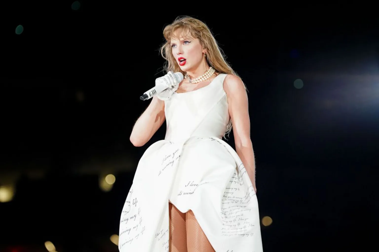 Getty Images Taylor Swift wears a white gown with cursive writing printed on it as she performs onstage during "Taylor Swift | The Eras Tour" at Caesars Superdome on 25 October 2024 in New Orleans, Louisiana.