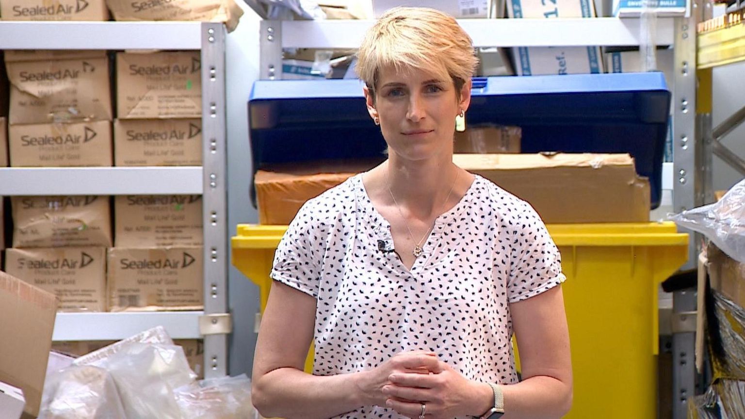 Reporter Fiona Irving standing in front of seized medication in a warehouse