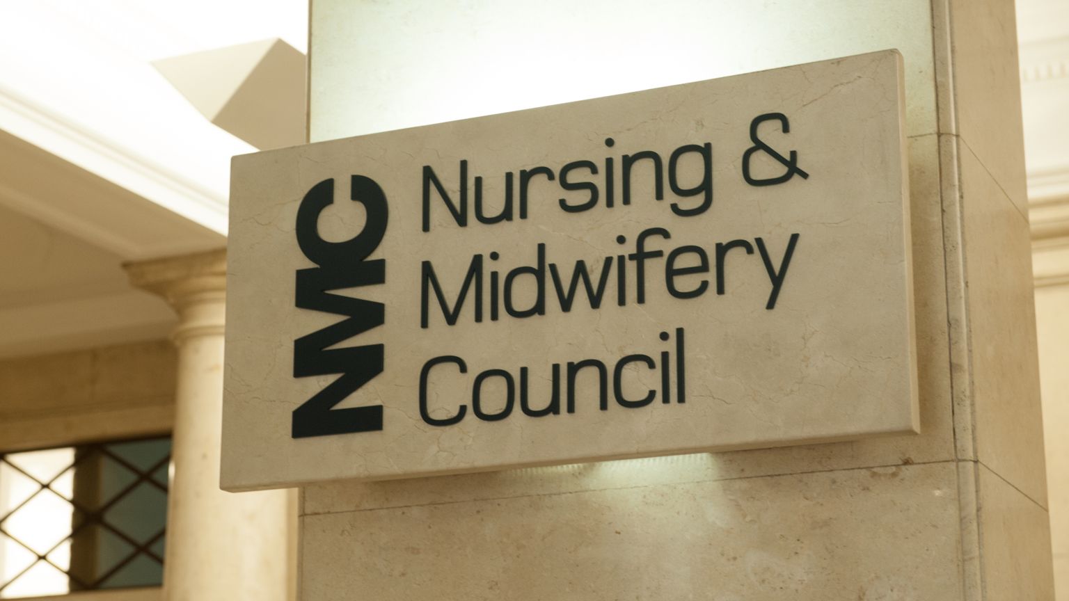 The Nursing and Midwifery Council sign on a beige, stone column 