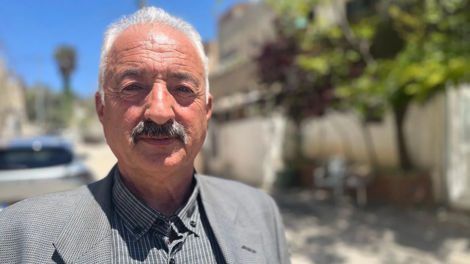 Fakhri Abu Diab, a middle-aged man with moustache, looks at the camera in a street in Jerusalem.
