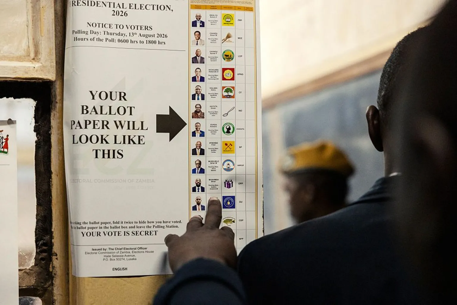 AFP via Getty Images A specimen ballot paper is fixed to the wall. The back of a person's head can be seen as they look at the choice on offer.