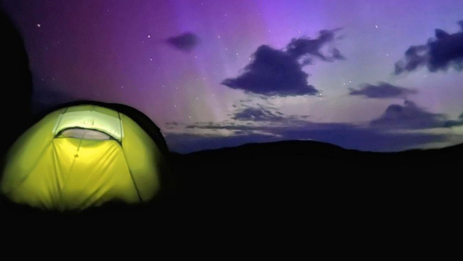 A tent pitched up with the Northern Lights visible