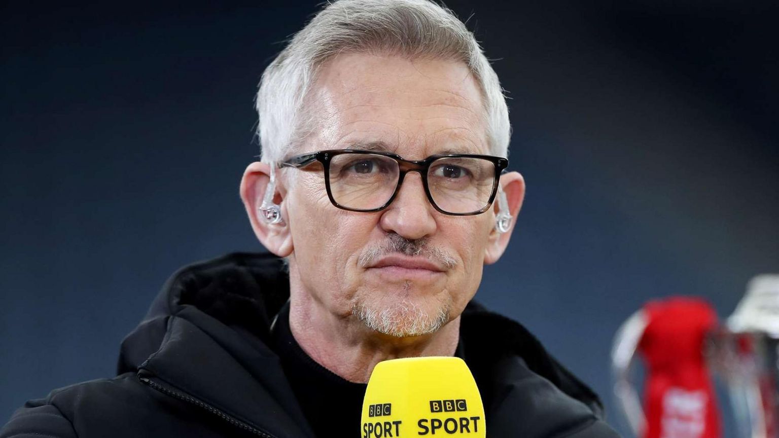 Gary Lineker presenting at the FA Cup final with his microphone with the cup in the background