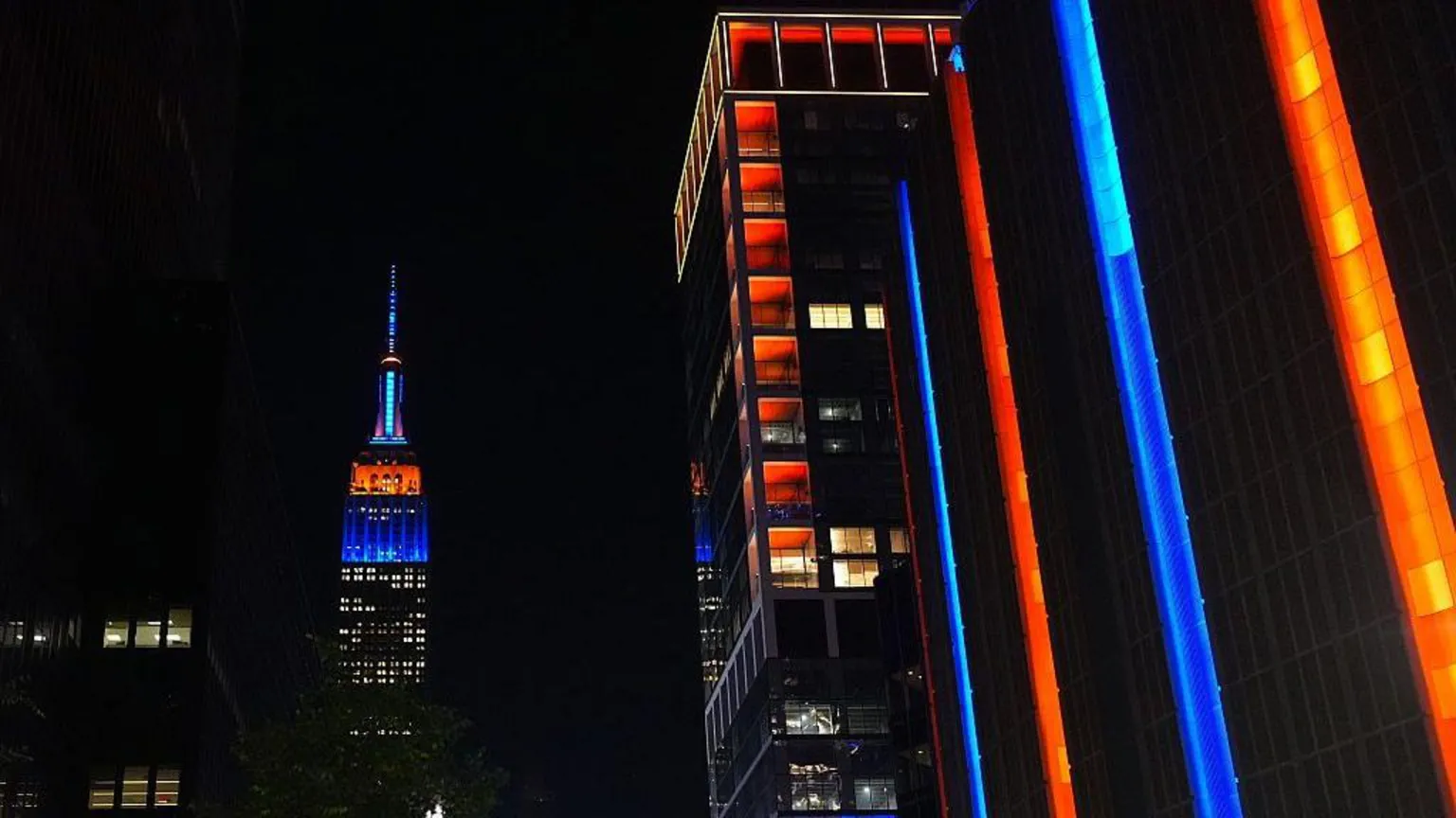 Anadolu via Getty Images City skyscrapers lit up in orange and blue amid night sky