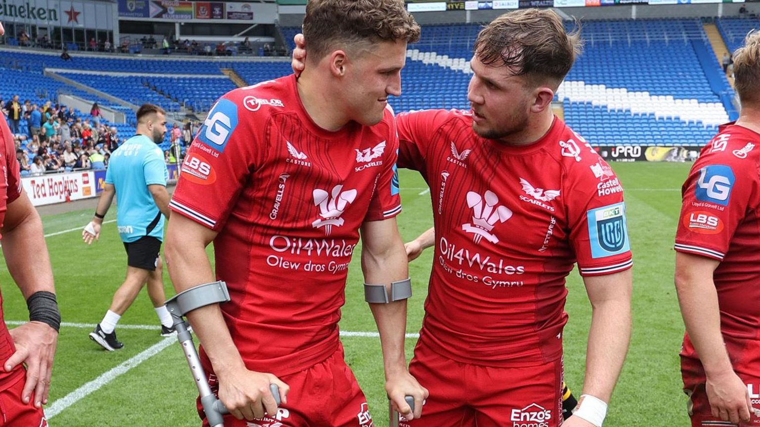 Tomi Lewis is consoled by Ioan Lloyd after being on crutches and having his foot in a protective boot after helping Scarlets beat Dragons