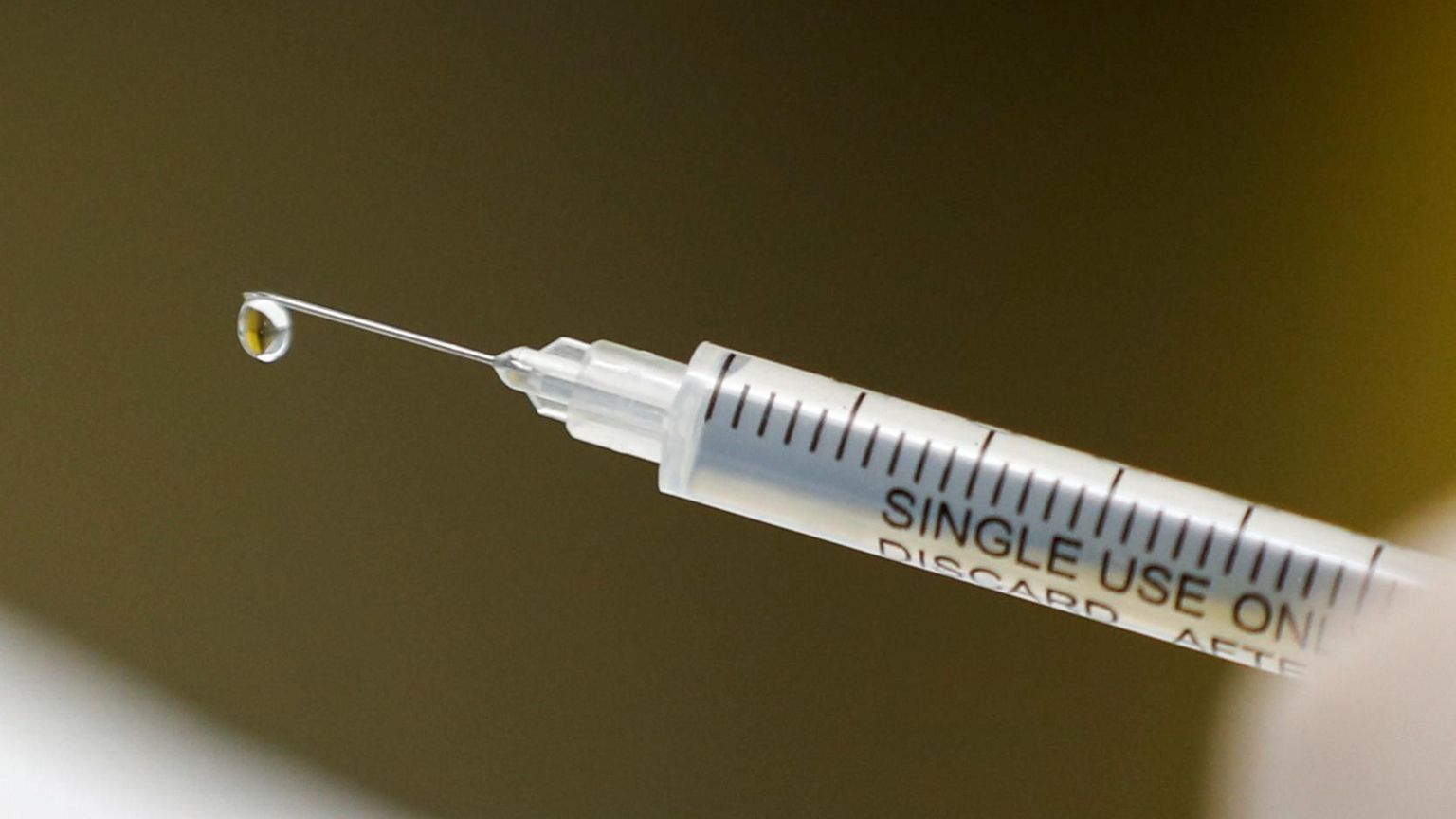 Close-up of a syringe with droplet at needle tip