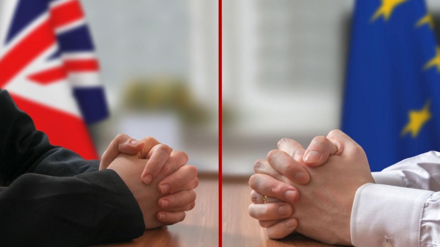 Two men's hands across a negotiating table, in front of UK and EU flags