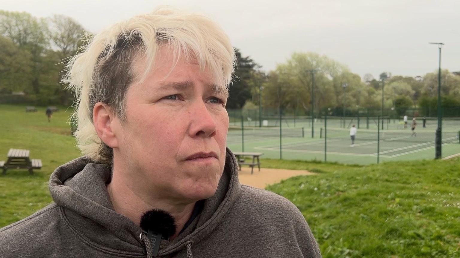 Carolyn Job stands with tennis courts behind her