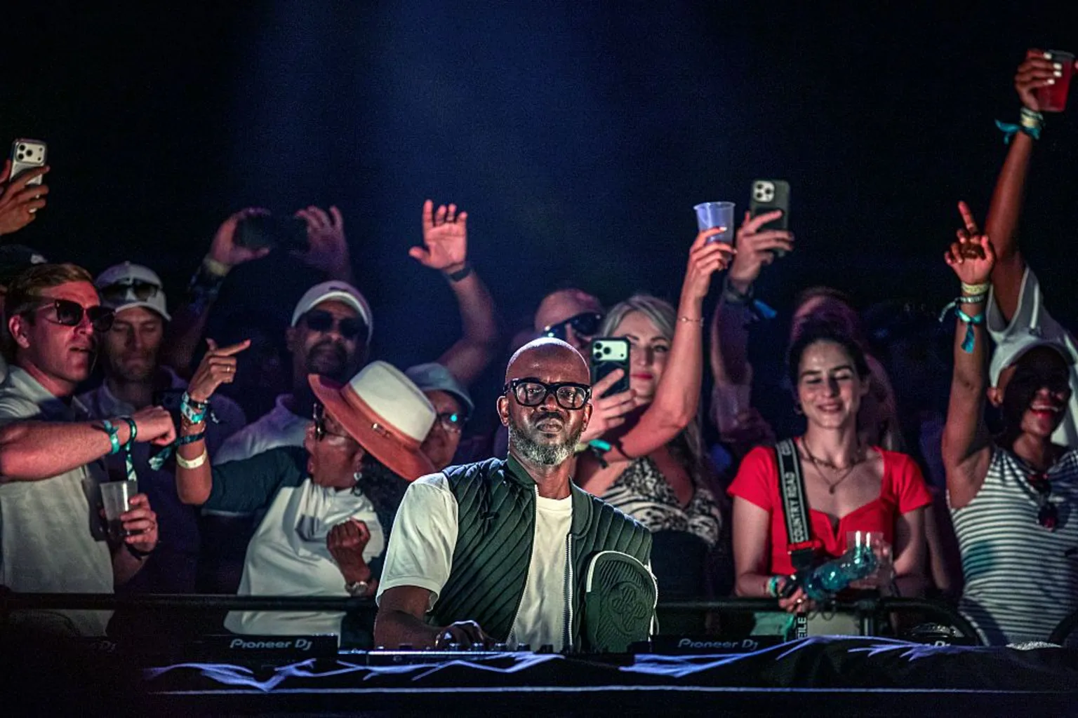 Getty Images South African DJ Black Coffee performs for fans on his DJ decks. Fans are seen in the background dancing.