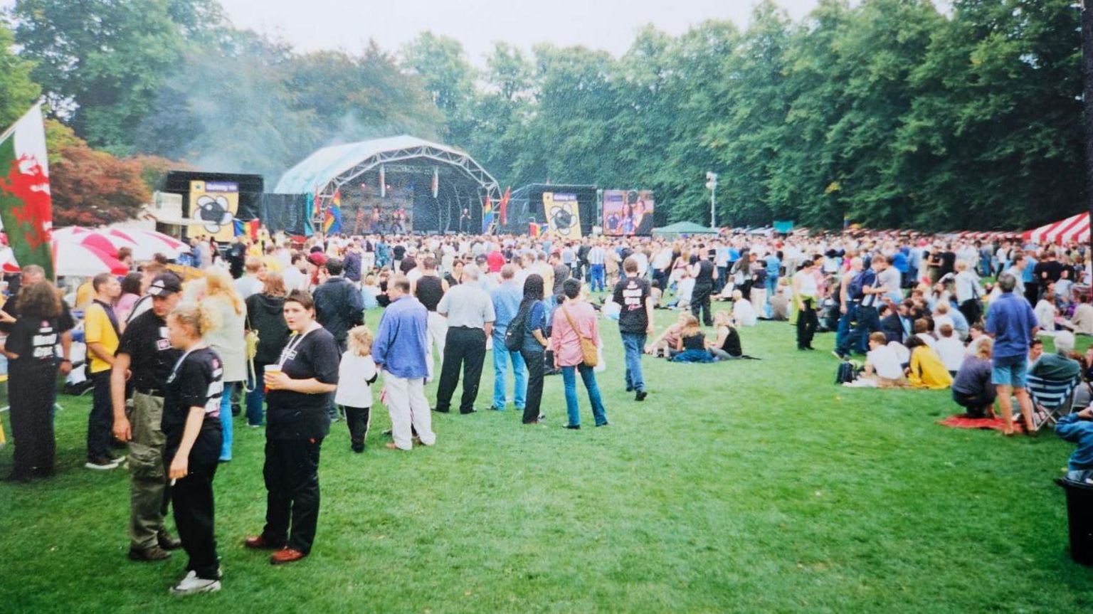 People gathered in the park with a stage at the back of the photo