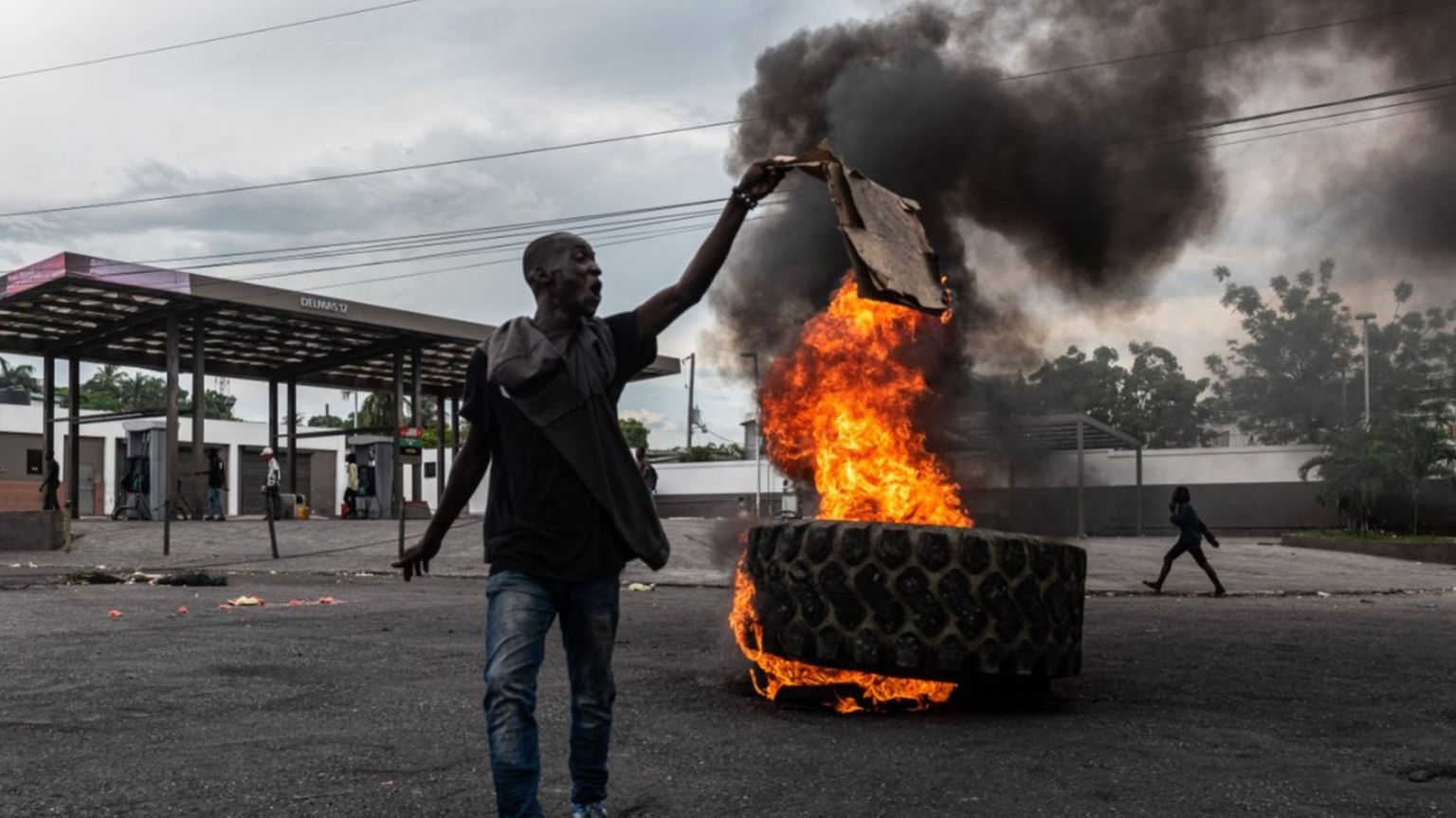 A man with a burning tyre in the background