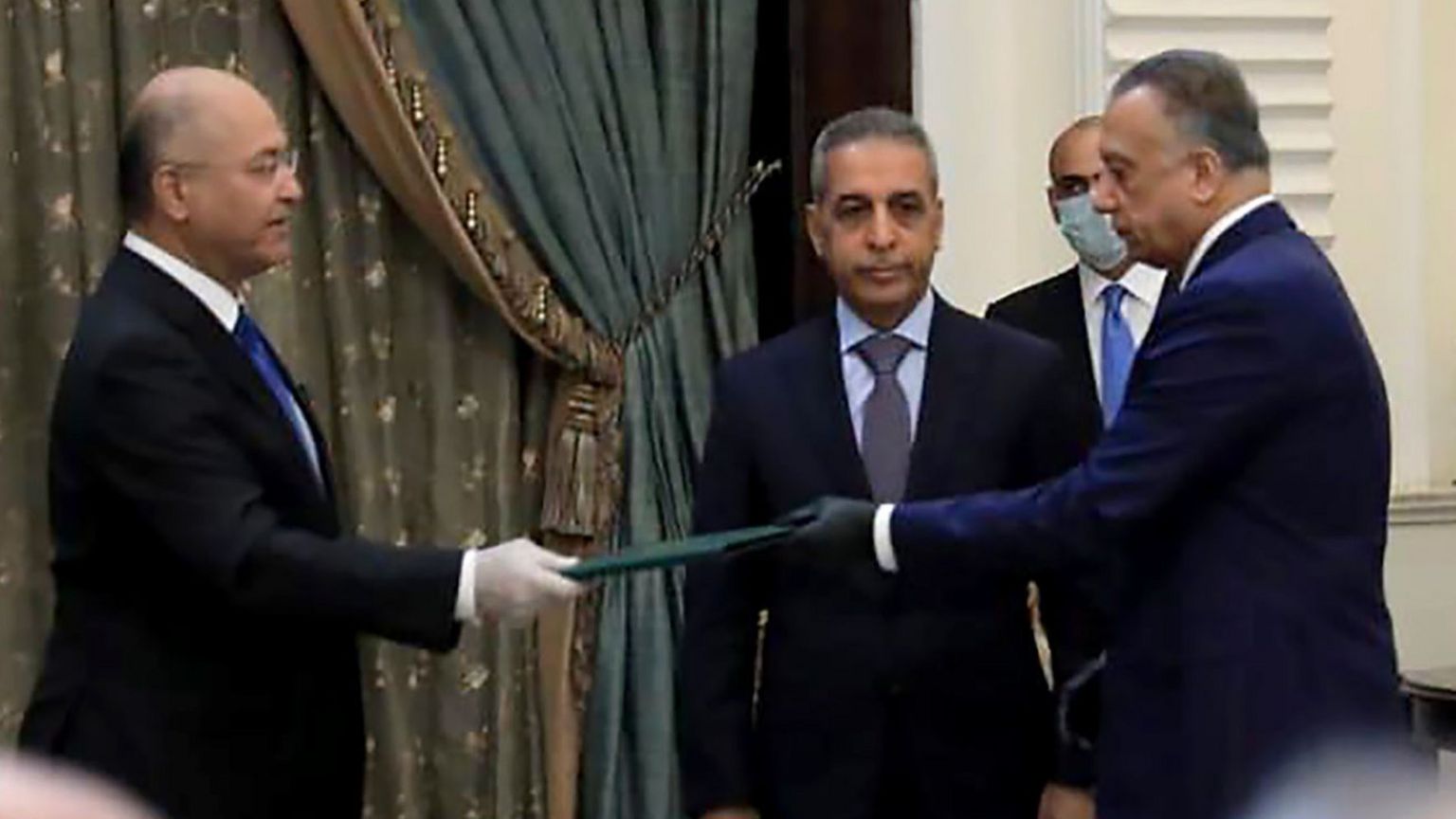 President Barham Saleh (L) and Mostafa al- (R) wore gloves at the ceremony