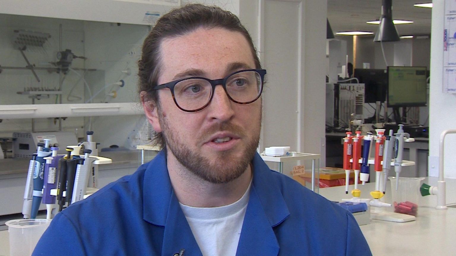 Man in a blue lab coat in a university chemistry lab