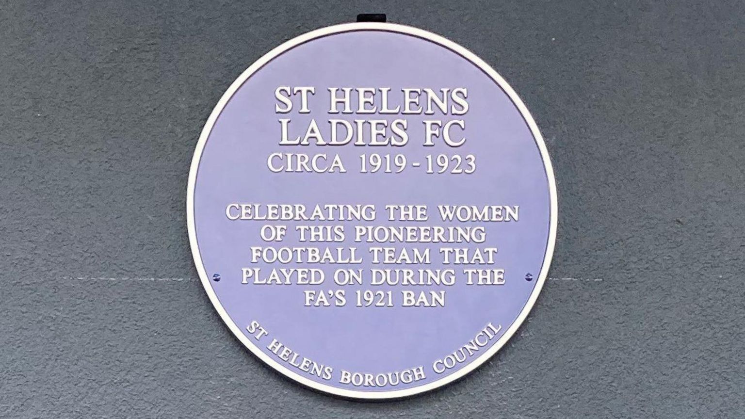 Blue plaque which reads: St Helens Ladies FC Circa 1919-1923. Celebrating the women of this pioneering football team that played on during the FA's 1921 ban. St Helens Borough Council