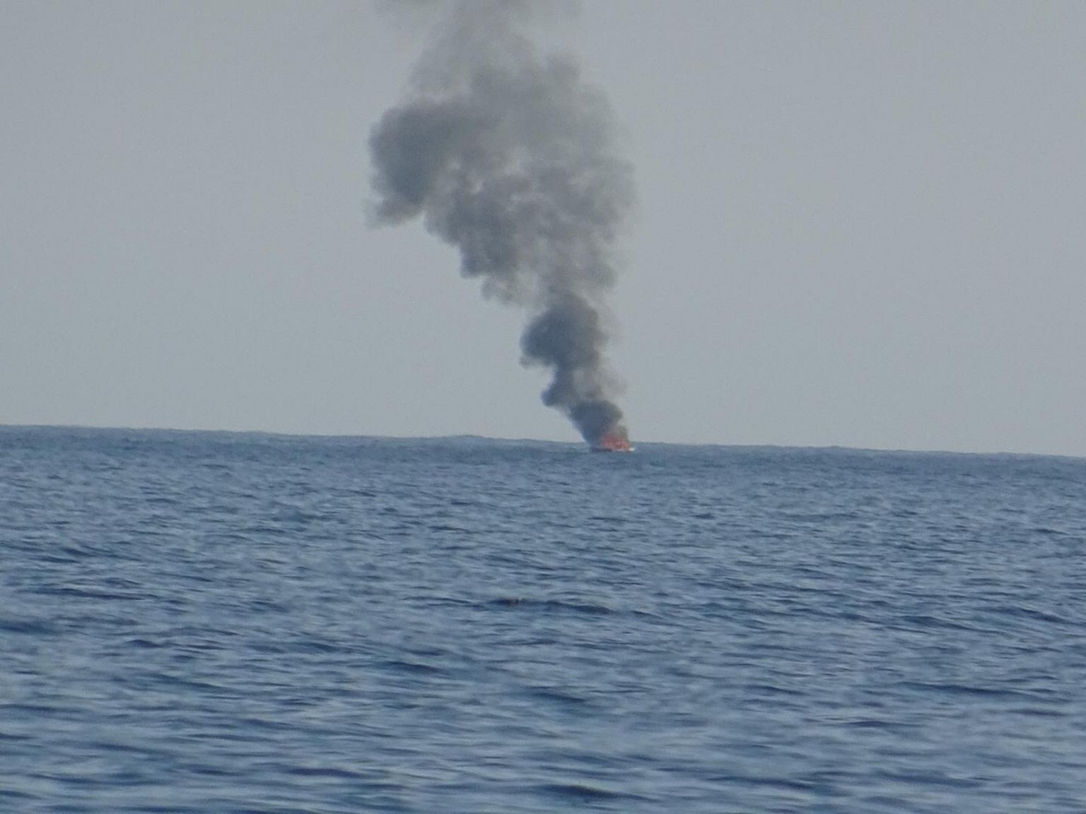 Plumes of smoke rise from boat at sea