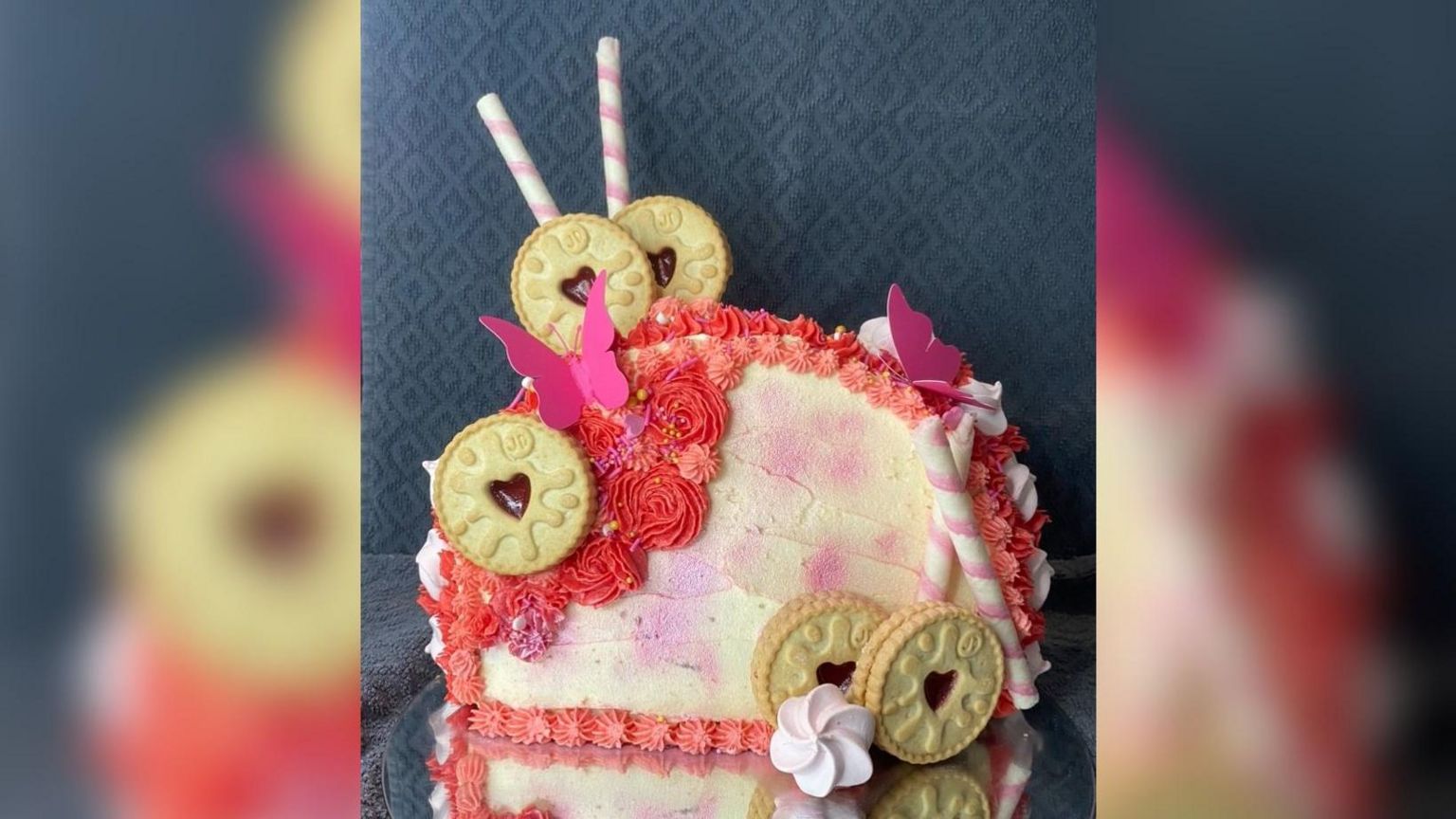 A pink cake decorated with Jammy Dodgers and paper butterflies.