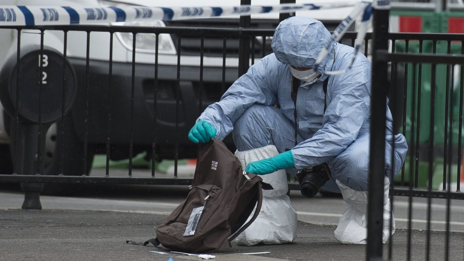 A forensics officer examining a rucksack