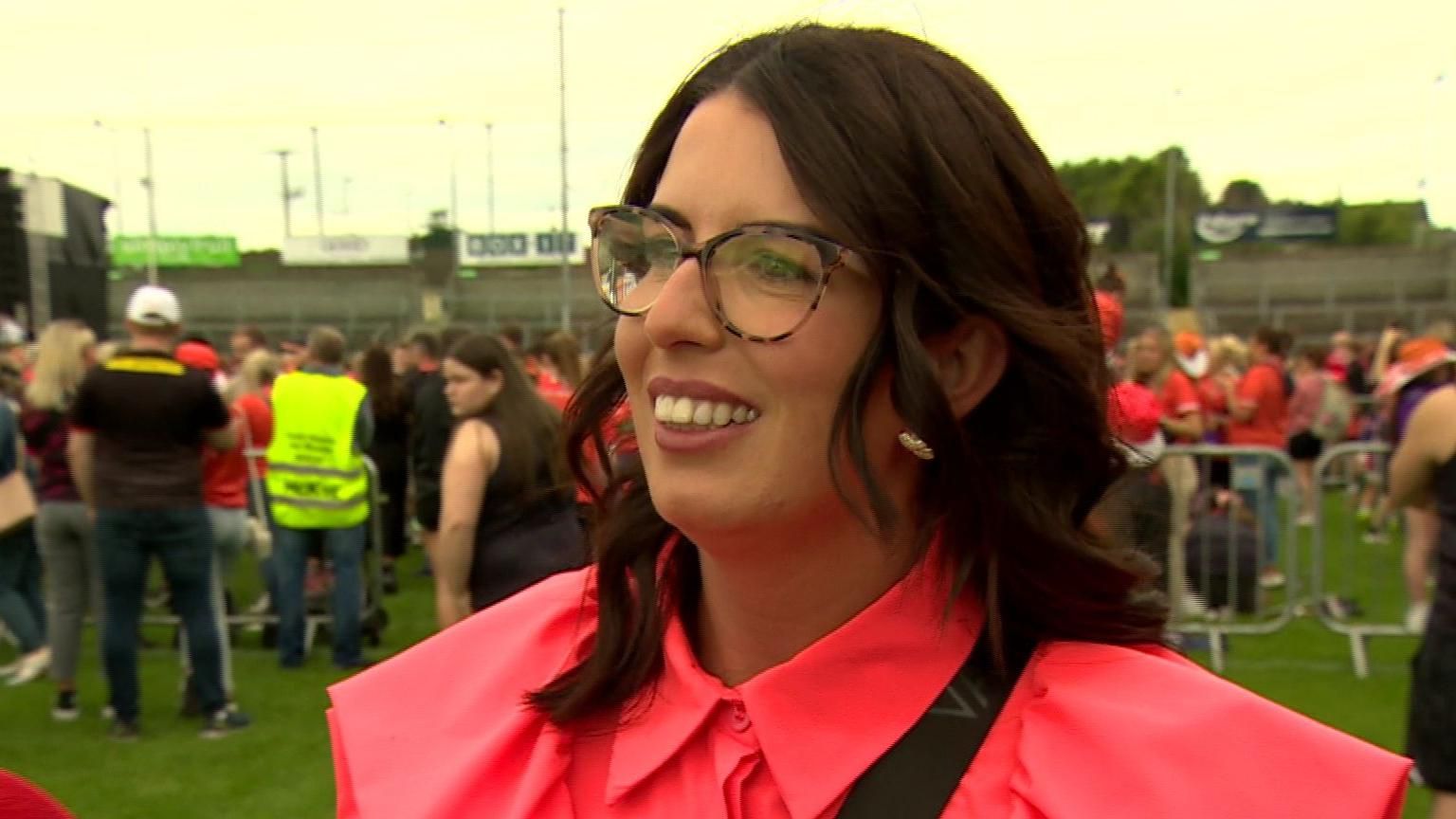 Brown haired woman with glasses and a pink top