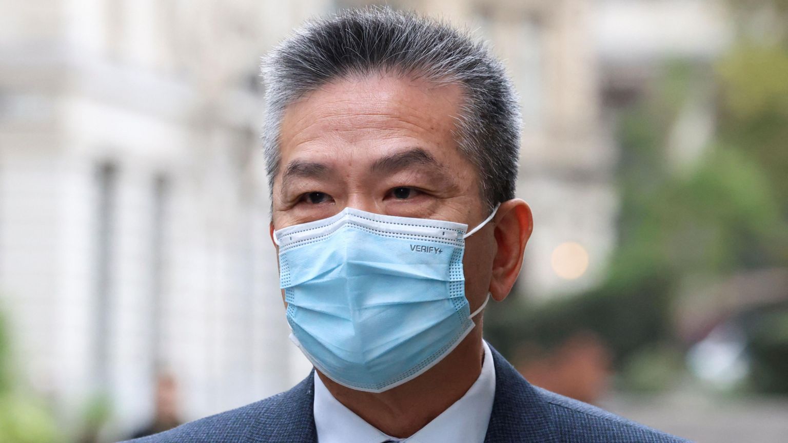 一名年长男子的头像。他有灰白短发,戴着蓝色口罩。