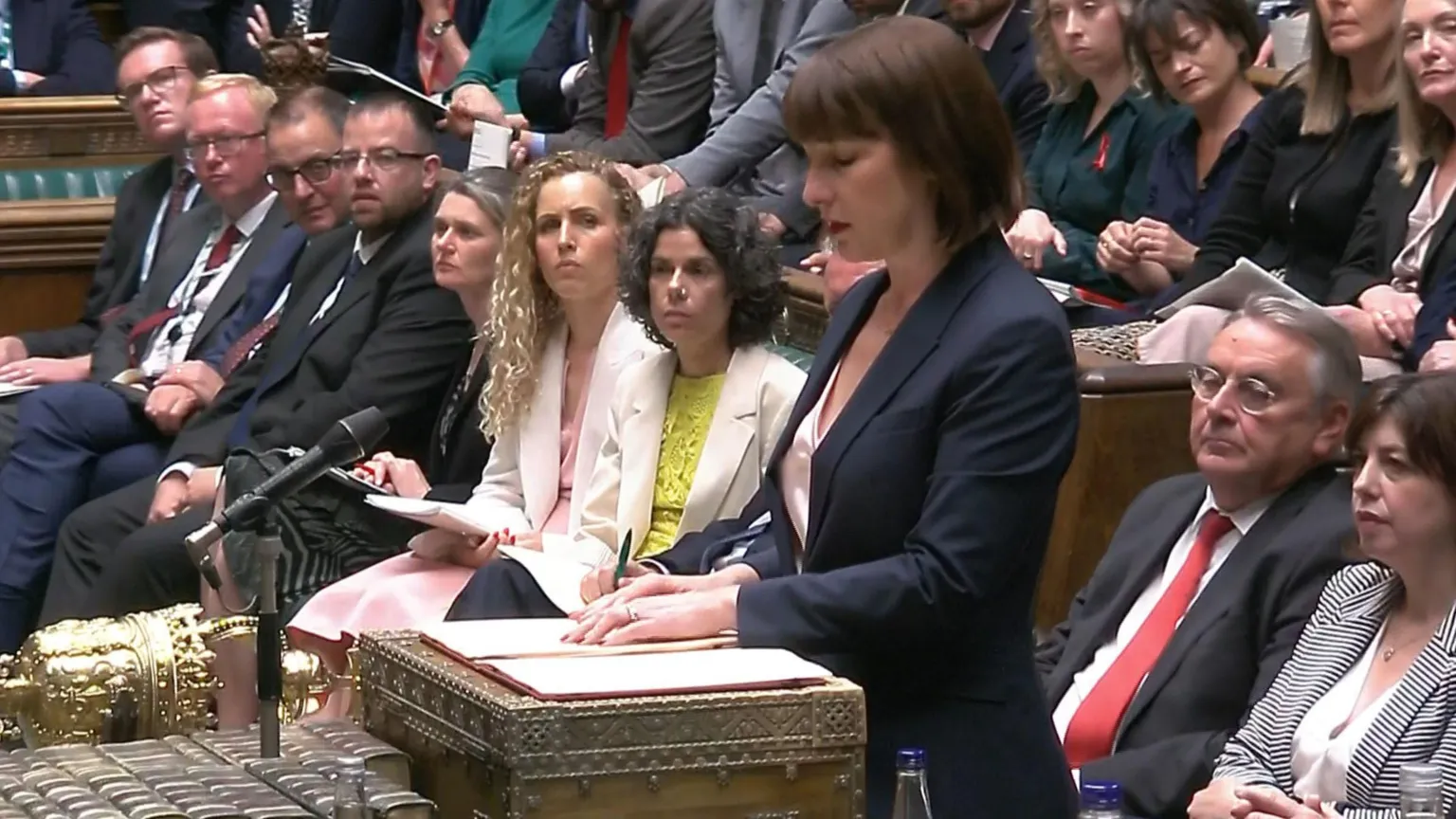 PA Rachel Reeves standing in Parliament surrounded by MPs who are watching her from the benches