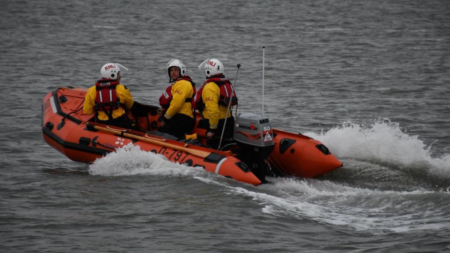 Three RNLI volunteers onboard a lifeboat at sea