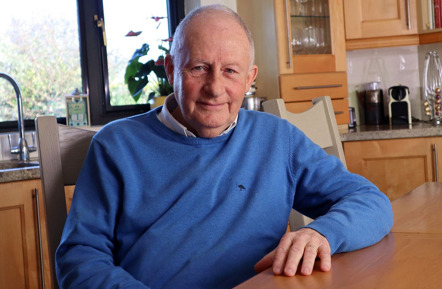 Safeguarding expert Ian Elliott, wearing a blue pullover, seated at a kitchen table 