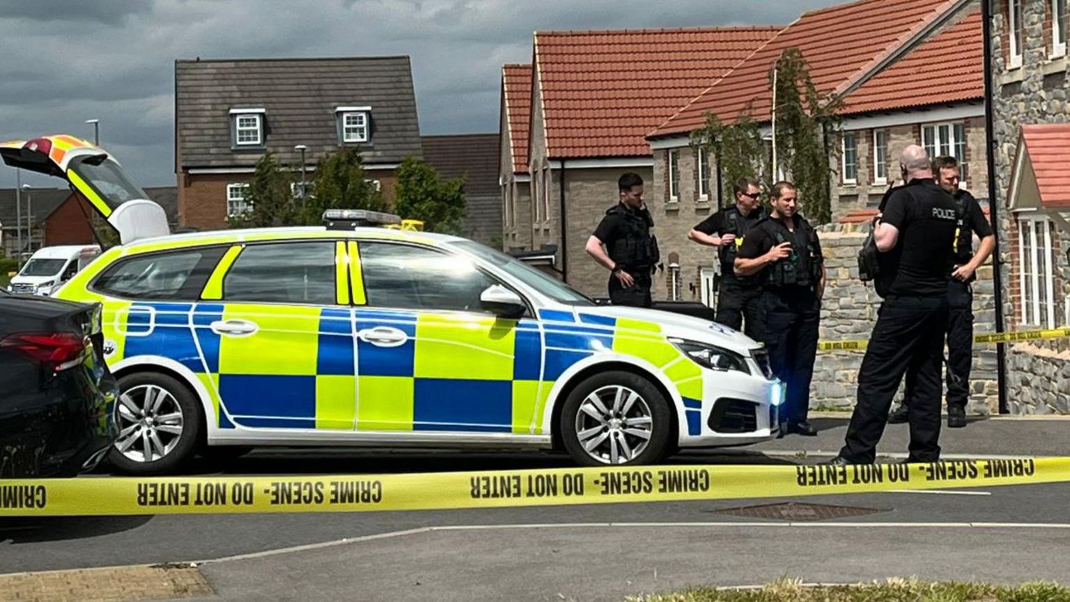 A police car on a street with offers standing beside it