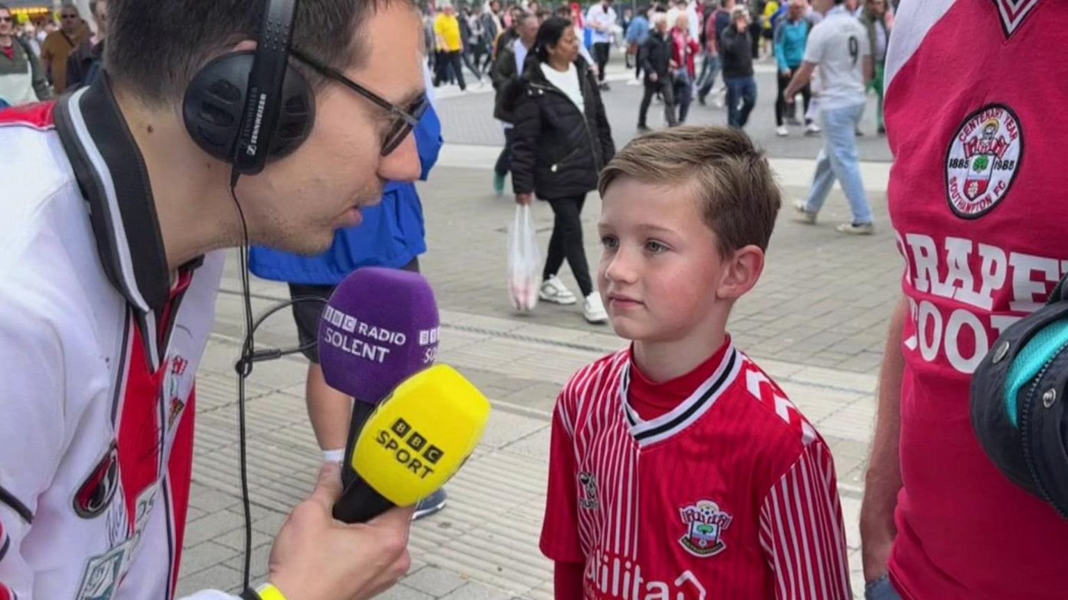 boy in Saints kit speaking to radio reporter