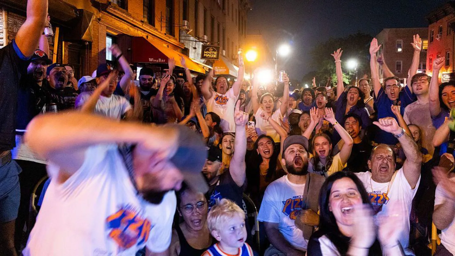 Corbis via Getty Images Dozens of fans cheering and watching a basketball game in the street