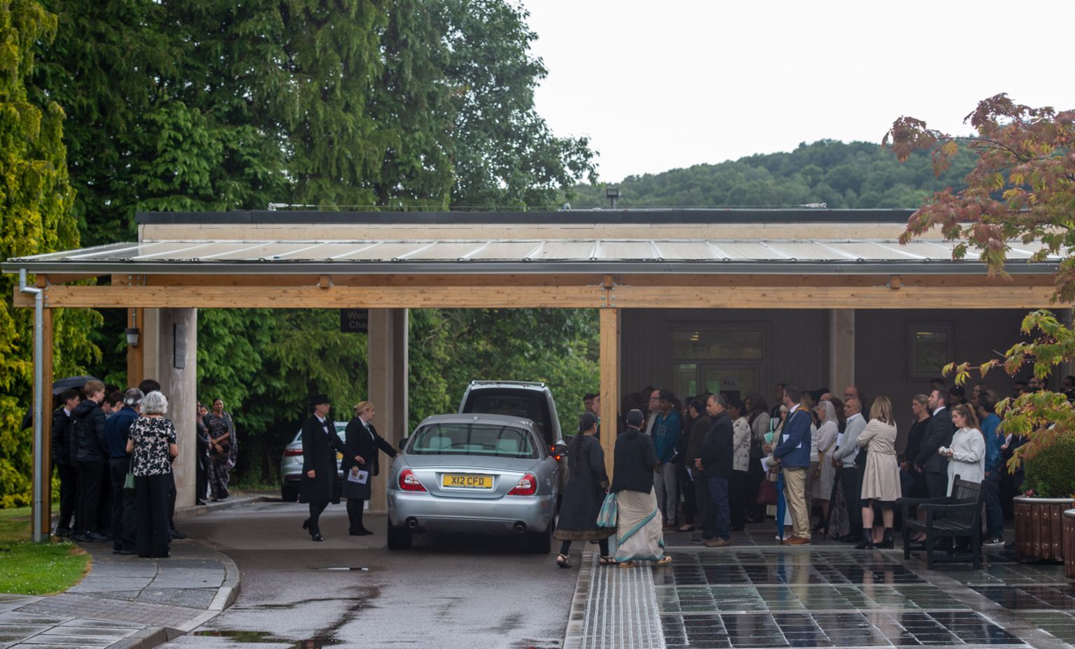 Mourners watch as funeral cortege arrives at service