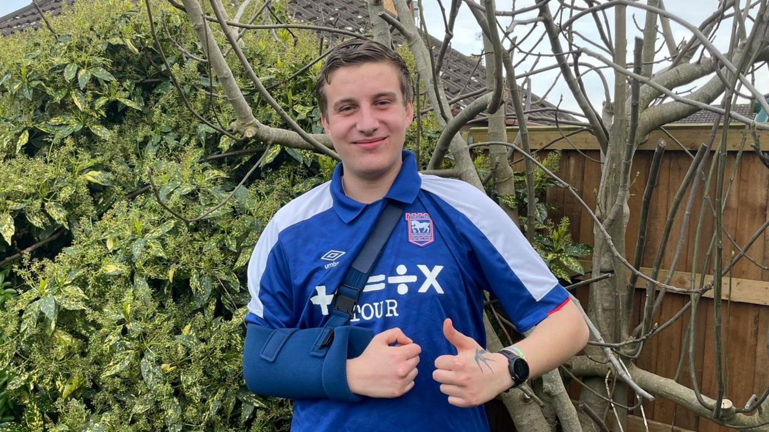 Rémi Mills poses with his shoulder bandage after dislocating his shoulder at an Ipswich Town game