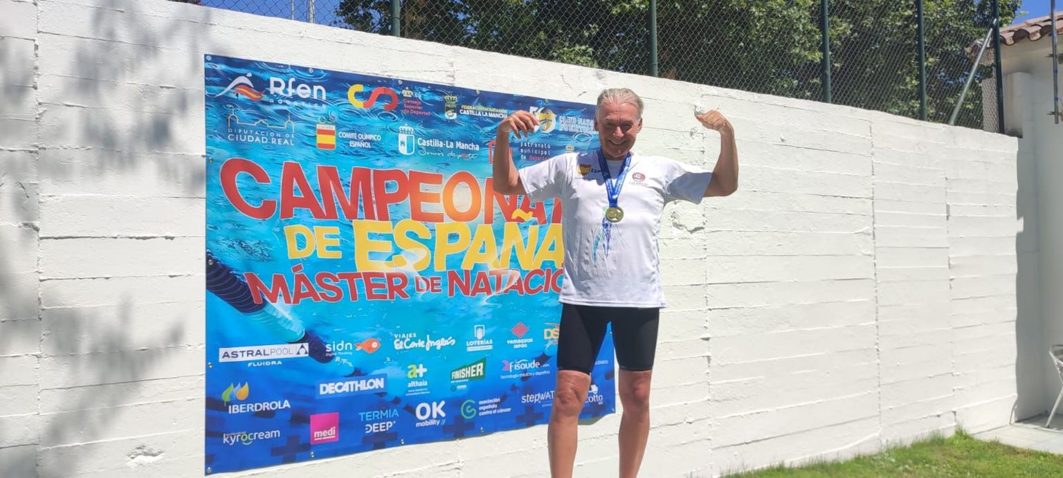 Nick Parkes pictured in a white T-shirt and black shorts with a medal around his neck cheering after a win at a Spanish swimming championship