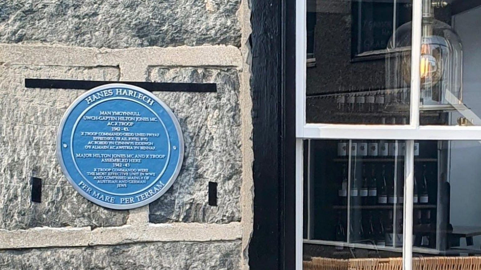 Circular blue plaque on stone wall next to six-over-six sash window