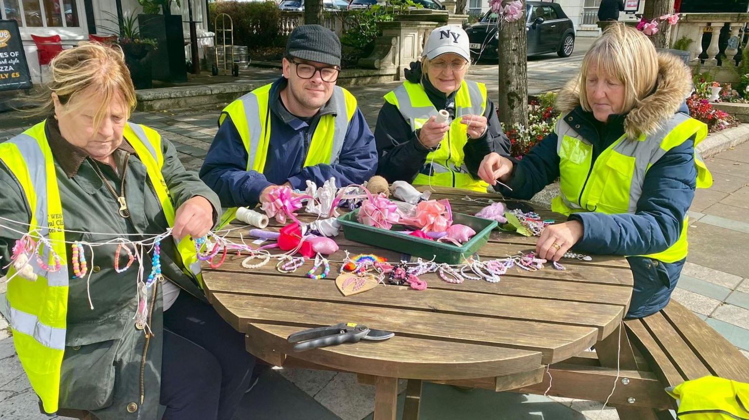 Four Lord Street in Bloom volunteers, dressed in high viz jackets, seated at a round table