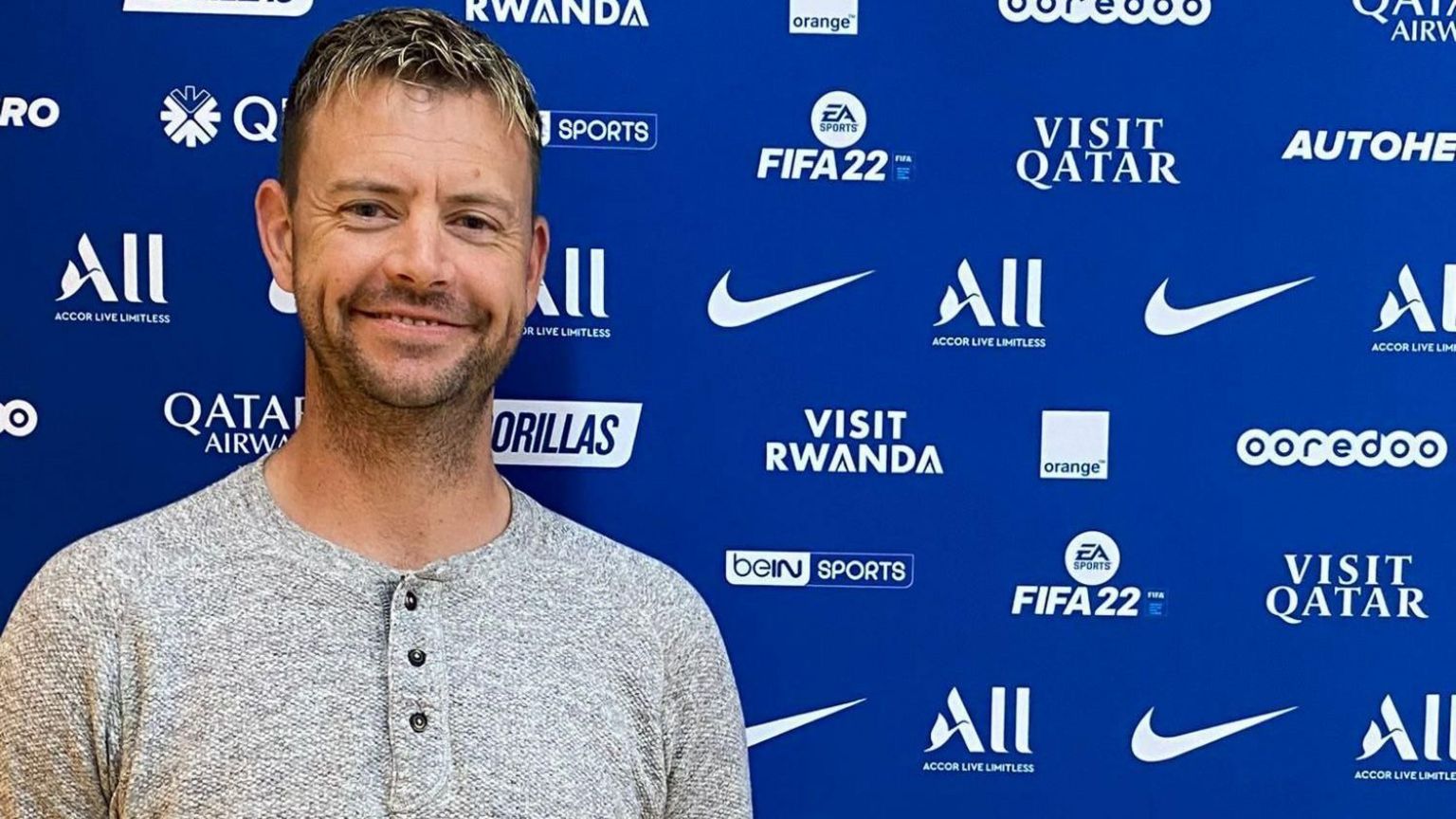 Si Collinson standing in front of a blue advertising board