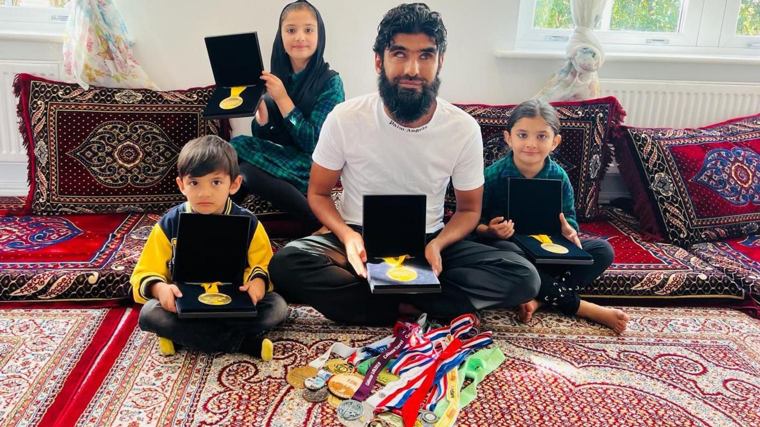 Wali with his three children, his trophies and medals