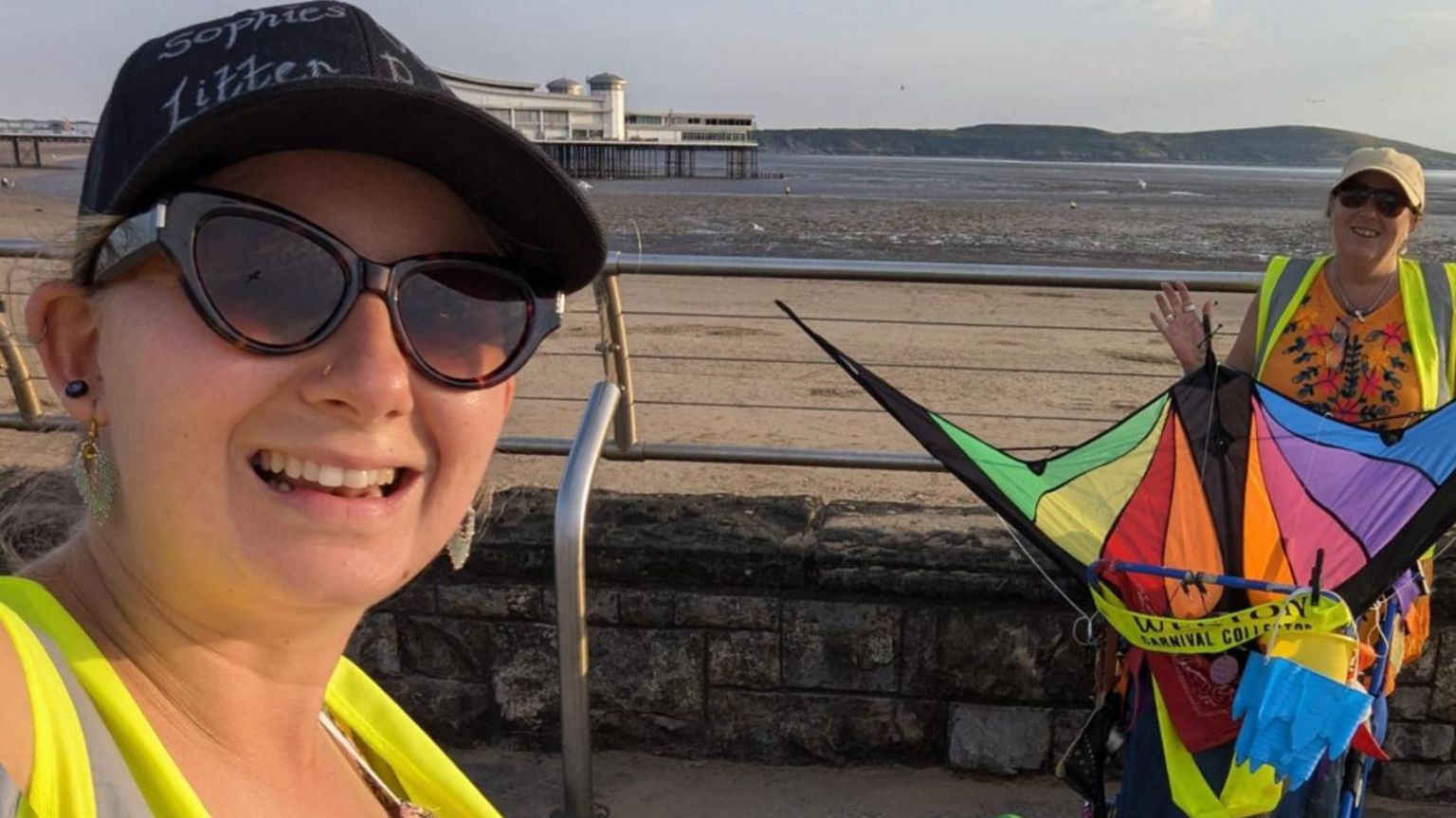 Ms Newton taking a selfie wearing a yellow hi-vis vest with Weston-super-Mare's beach and pier in the background