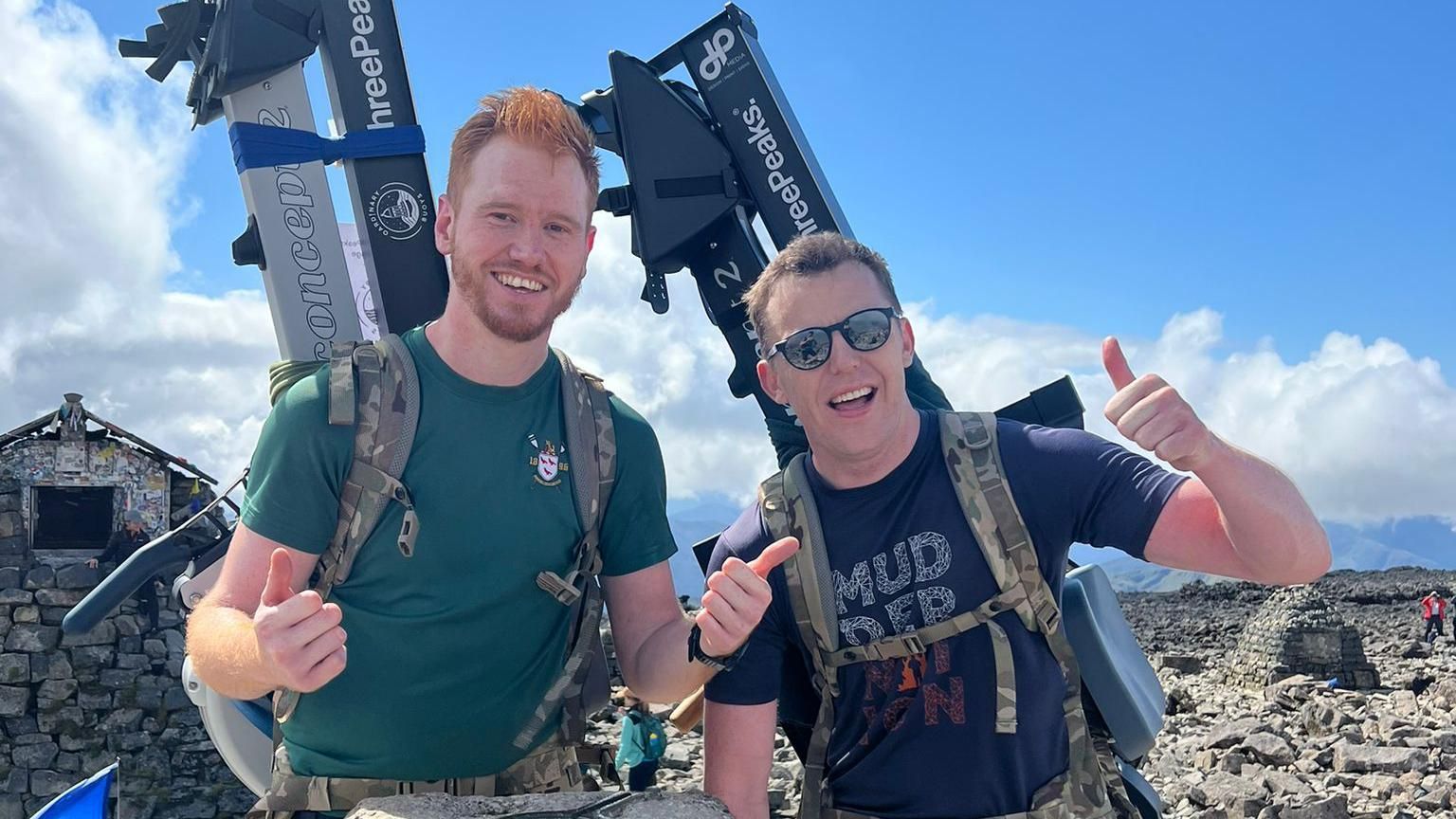 Scott Brown and Dafydd Helps-Fursse at the top of Ben Nevis carrying rowing machines on their backs