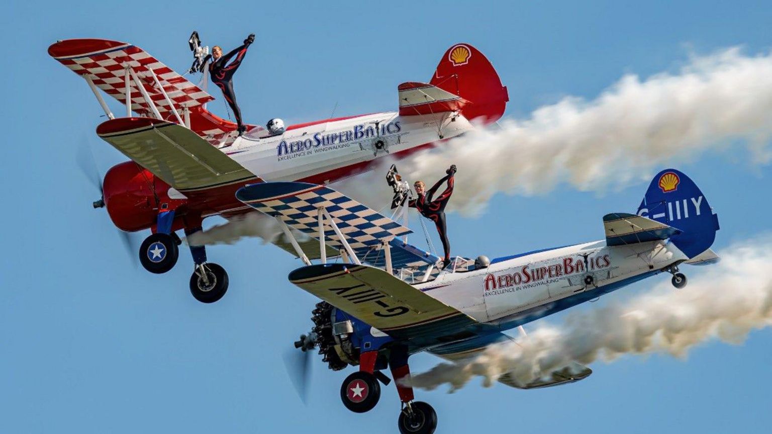 Two people performing on the wings of two planes, doing gymnastics