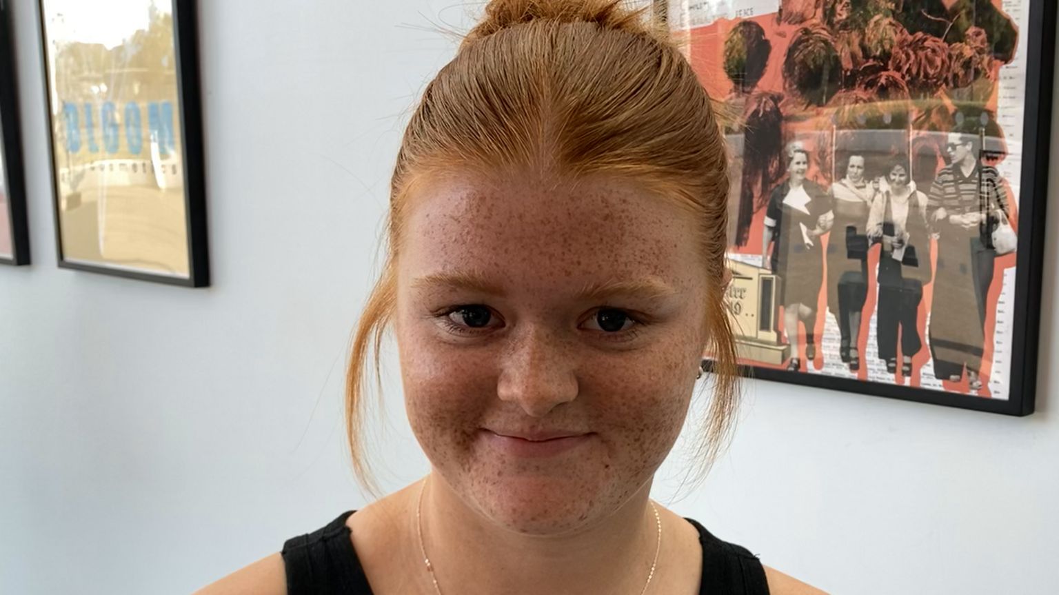 Molly Moore, who has long red hair tied back and freckles, smiles at the camera