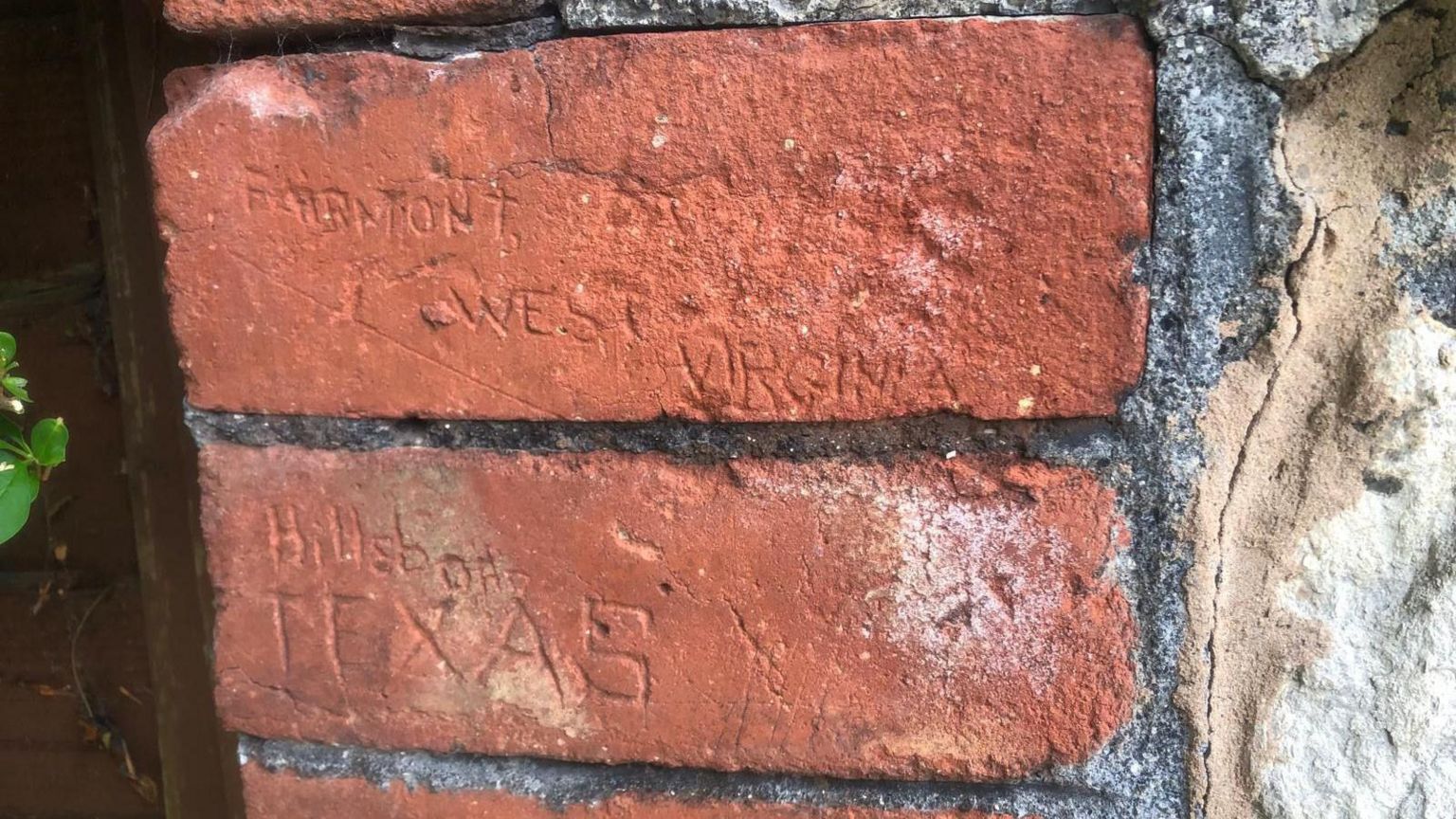A red brick wall with American place 'Hillsboro Texas' inscribed on. 