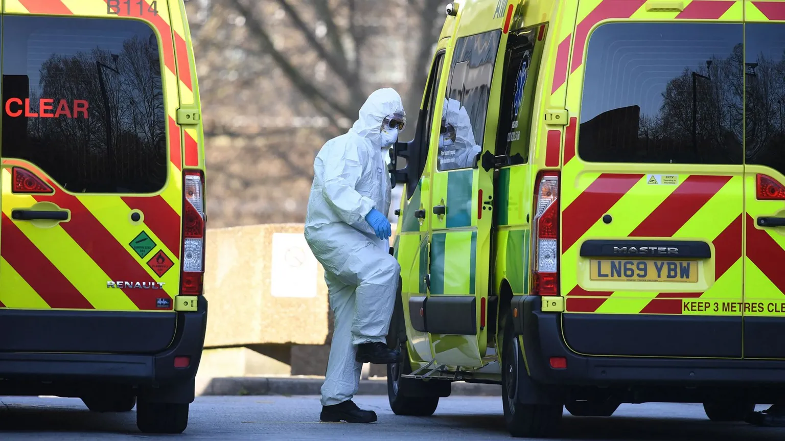 AFP via Getty Images A healthcare worker in white haz mat gear climbs into an ambulance after loading in a patient (not pictured) outside St Thomas' Hospital in March 2020.