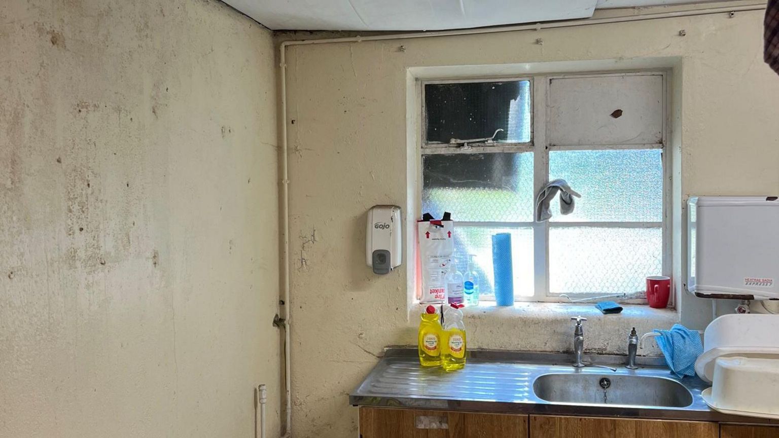 A kitchen in the hub building with a missing window and deteriorating walls