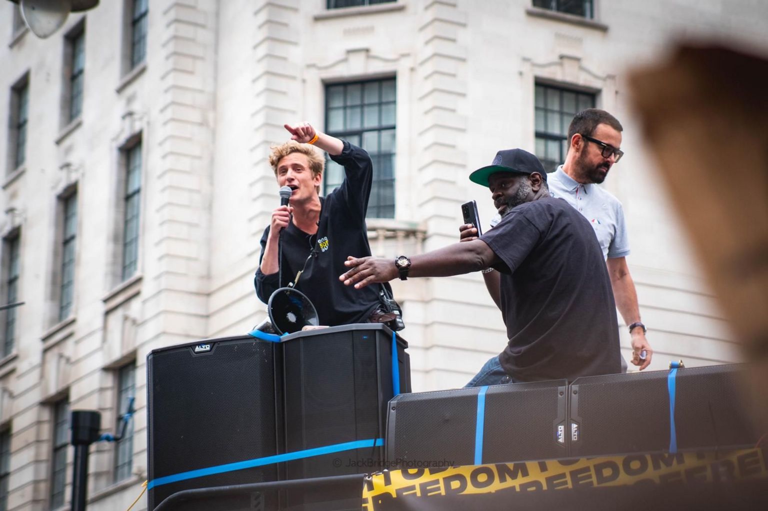 George FLeming speaking into a microphone on a soundsystem outside